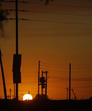 the sun is setting behind power lines and telephone poles